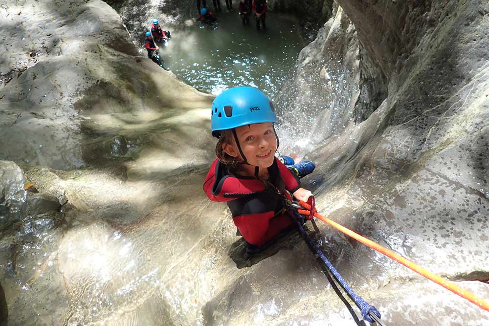 enfant qui descend en canyoing une cascade à annecy