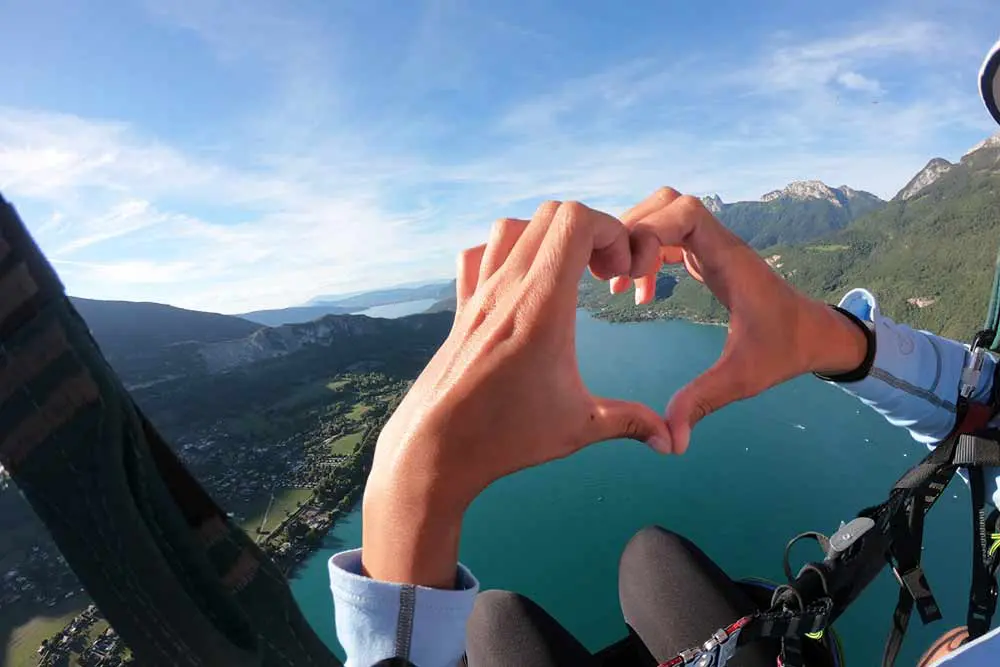 un coeur formé par les doigts en parapente à Annecy