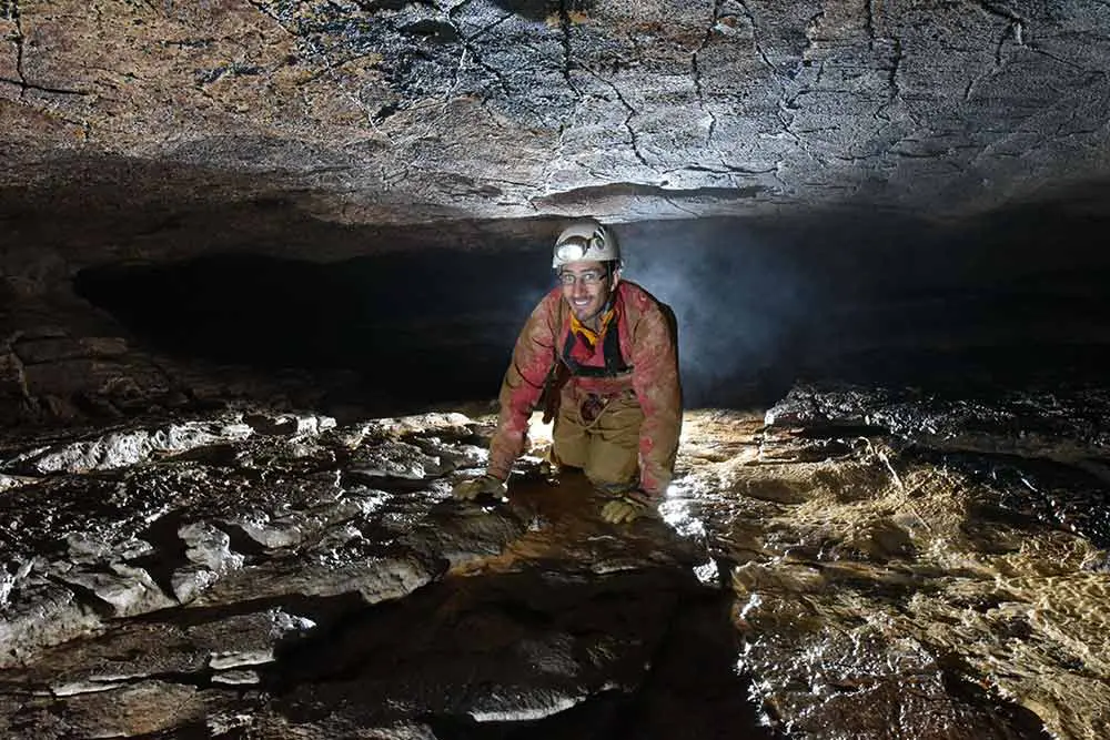 homme qui rampe en spéléologie à annecy